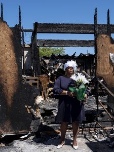 Woman stands in remains of church burned down due to a hate crime