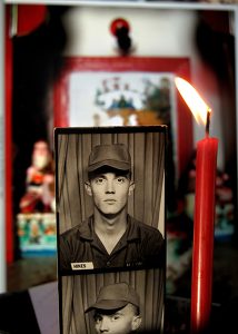 Photobooth strip is photographed next to a burning candle