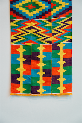A three-strip-wide Kente handwoven textile from Ghana with brightly colored geometric patterns in red, yellow, green, blue, and purple.