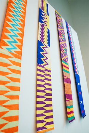 Four single-panel Kente cloths from Ghana, each featuring distinct geometric patterns in bright, contrasting colors.