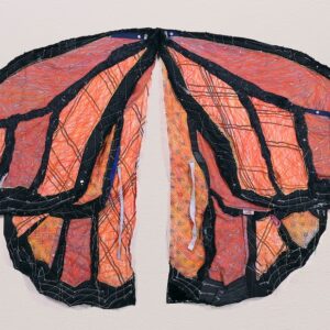 A pair of black and orange monarch butterfly wings made of textured fabrics and other various textures.