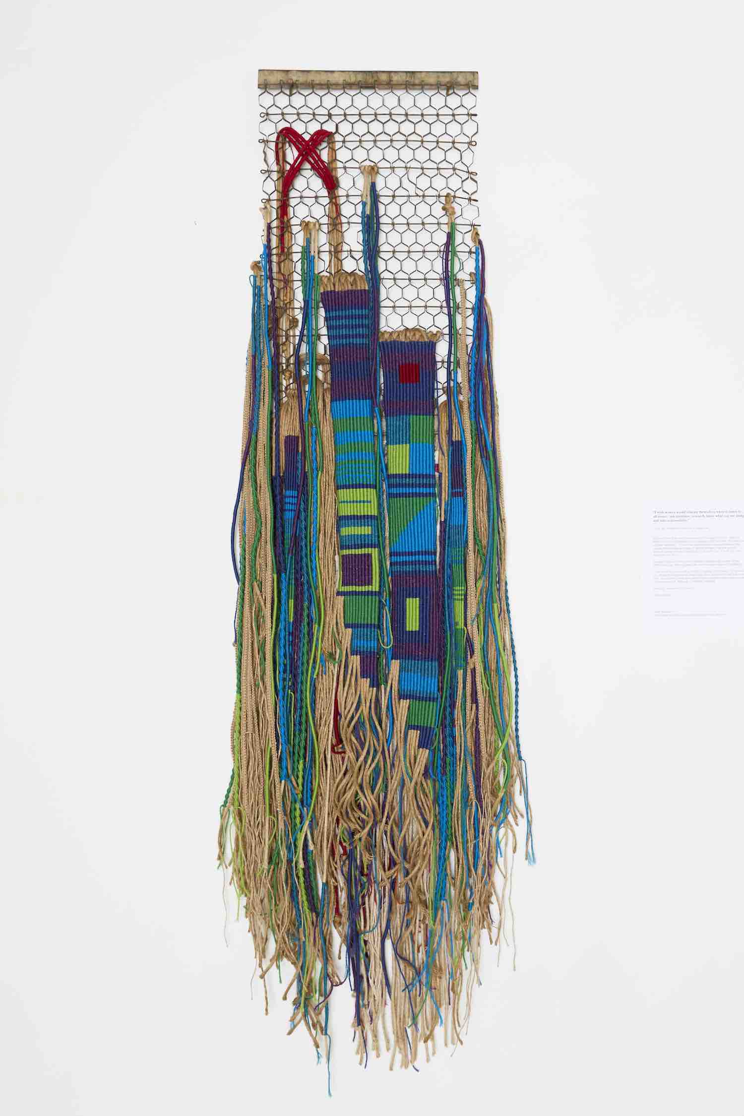 Spun wool of various colors hang from an old boot scraper/doormat.